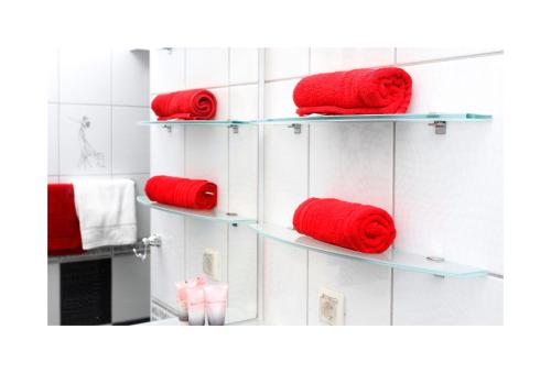 4 estanterías con toallas rojas en el baño en Sarajevo Apartments No.5, en Sarajevo