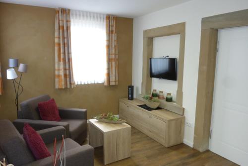 a living room with two chairs and a television at Weinhotel Stadtmühle beim Weingut Schauß in Monzingen