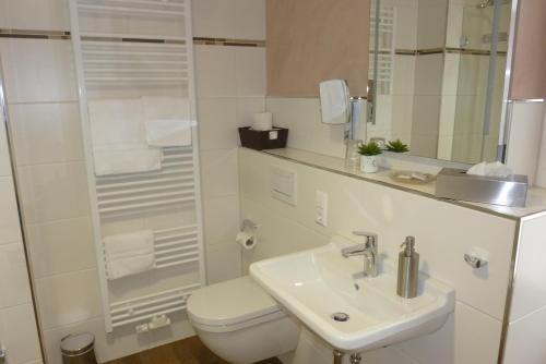 a white bathroom with a toilet and a sink at Weinhotel Stadtmühle beim Weingut Schauß in Monzingen