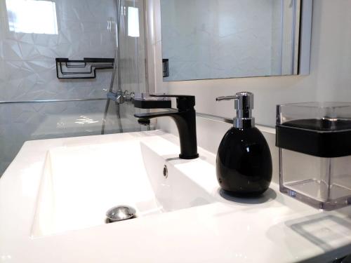 een wastafel in de badkamer met een zeepdispenser en een zwarte fles bij Apartment Portonovo Paraiso II - Sea View - Piscina - Wifi - Old Town in Puerto del Carmen