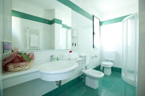 bagno bianco con lavandino e servizi igienici di Hotel Falcone a Lignano Sabbiadoro