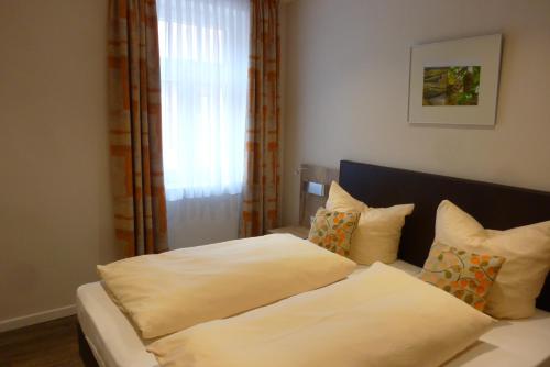 Monzingen的住宿－Hotel-Garni Stadtmühle，卧室配有带枕头的床铺和窗户。