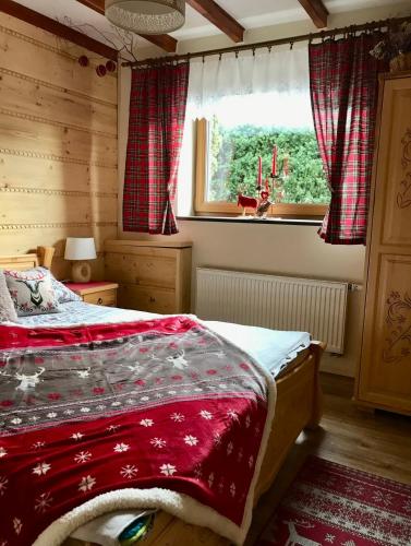 a bedroom with a bed with a red blanket and a window at Świstakówka in Szczyrk