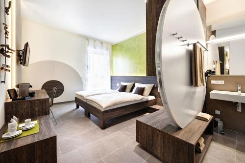 Schlafzimmer mit einem Bett, einem Spiegel und einem Waschbecken in der Unterkunft eee Hotel Marchtrenk in Marchtrenk