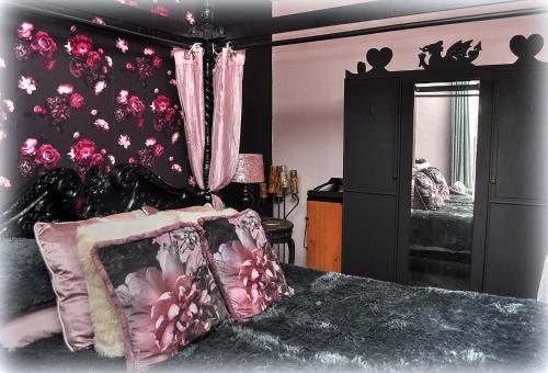 LlanegrynにあるPeniarth armsのベッドルーム1室(ピンクのカーテンと鏡付きのベッド1台付)