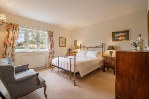 a bedroom with a bed and a chair and a window at Charming cottage in beautiful countryside with a boating lake - The Calf Pens in Ipswich