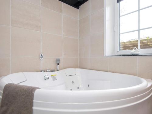 uma banheira branca na casa de banho com uma janela em 8 person holiday home in Haderslev em Haderslev