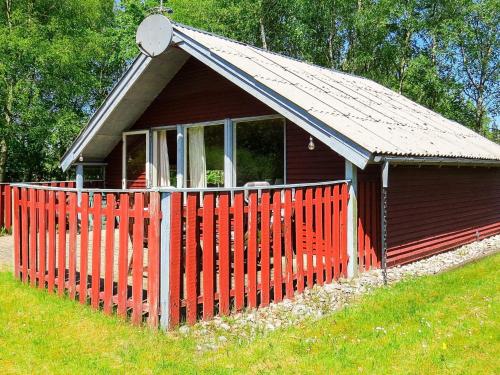 ein kleines rotes Haus mit einem roten Zaun in der Unterkunft 4 person holiday home in Hals in Hals