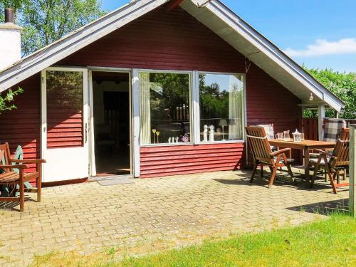 ein rotes Haus mit einer Terrasse mit einem Tisch und Stühlen in der Unterkunft 4 person holiday home in Hals in Hals