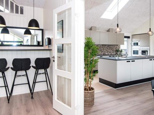 a kitchen with white cabinets and black stools at Luxury Retreat by the Sea - By Traum Ferienwohnungen in Sarup