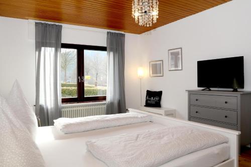 1 dormitorio con 1 cama, TV y ventana en Wrede, en Wenholthausen