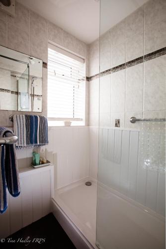 a white bathroom with a tub and a shower at The Old Dairy, Land's End, Sennen in Sennen