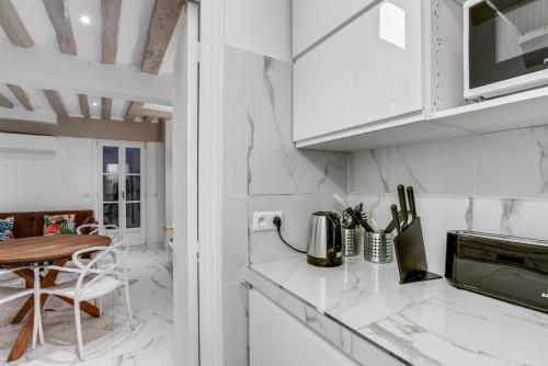 - une cuisine blanche avec des placards blancs et une table dans l'établissement Best Location Calm Palais Royal Louvre Opera Concorde CLIM, à Paris