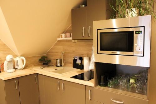 a kitchen with a microwave above a sink at Zengő Kincse SPA Vendégház Hosszúhetény in Hosszúhétény