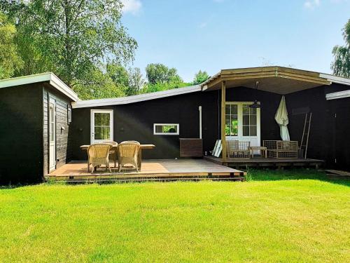 una casa negra con una mesa y sillas en una terraza en 6 person holiday home in Vejby, en Vejby