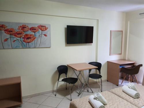 a room with a tv and a table and chairs at Anthena Studios in Skiathos Town