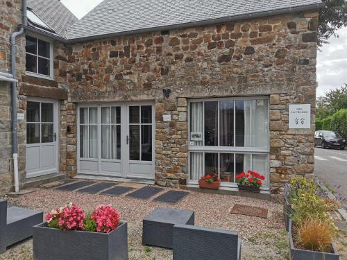 - un bâtiment en briques avec deux portes et quelques fleurs dans l'établissement Gîtes les 2 Hermines, à Mont-Dol