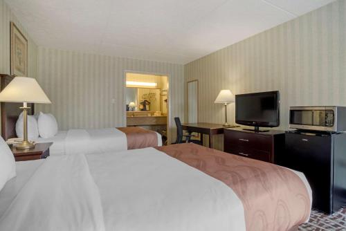 a hotel room with two beds and a flat screen tv at Quality Inn Fredericksburg near Historic Downtown in Fredericksburg