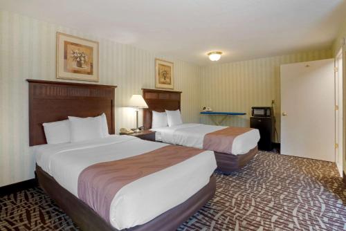 a hotel room with two beds and a bathroom at Quality Inn Fredericksburg near Historic Downtown in Fredericksburg