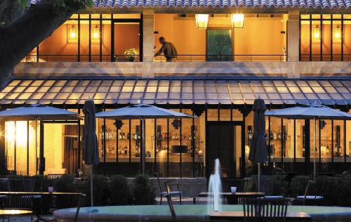 a restaurant with tables and umbrellas in front of a building at Domaine De Manville in Les Baux-de-Provence