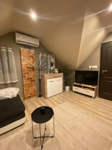 a living room with a couch and a tv at Zengő Kincse SPA Vendégház Hosszúhetény in Hosszúhétény