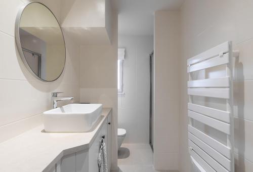 uma casa de banho branca com um lavatório e um espelho em LA PAUSA, Maison de ville avec Jardin centre de SAINT TROPEZ em Saint-Tropez