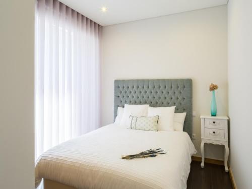 a white bedroom with a large bed with a blue headboard at Casas do Patio Country Houses & Nature in Caldas da Felgueira