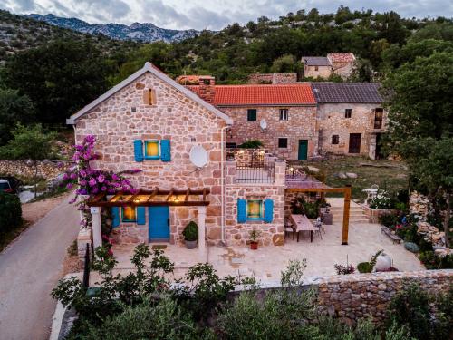 a large stone house with blue doors and a patio at Stone house Goranova kuća in Seline