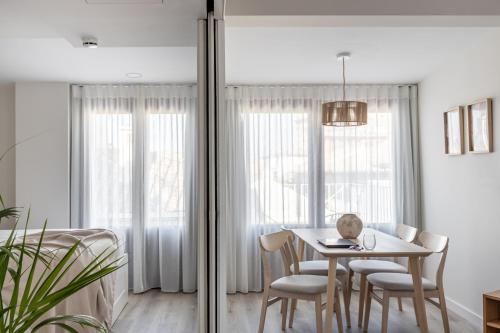 a white dining room with a table and chairs at Líbere Granada Catedral in Granada