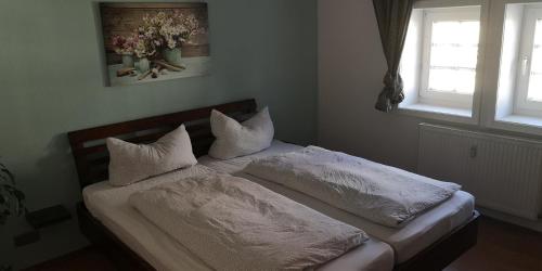 - un lit avec des draps et des oreillers blancs dans une chambre dans l'établissement Ferienwohnung/Monteurwohnung im Herzen von Ahnatal, à Weimar