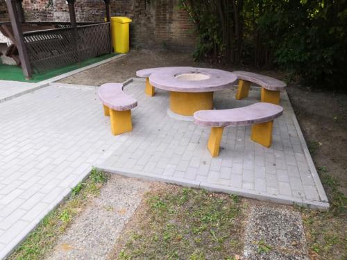 une table de pique-nique et trois bancs assis sur un terrain de briques dans l'établissement Kupa Villa, à Balatonboglár