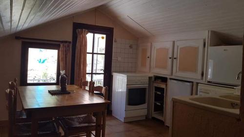 a kitchen with a wooden table and a large window at Location Cap corse in Canari