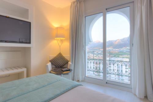 a bedroom with a bed and a window with a balcony at Al Mandari Hôtel Tétouan in Tétouan