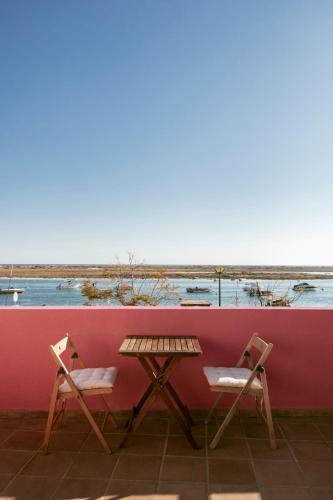 a table and two chairs next to a red wall at Casa Viana - Guesthouse in Cabanas de Tavira