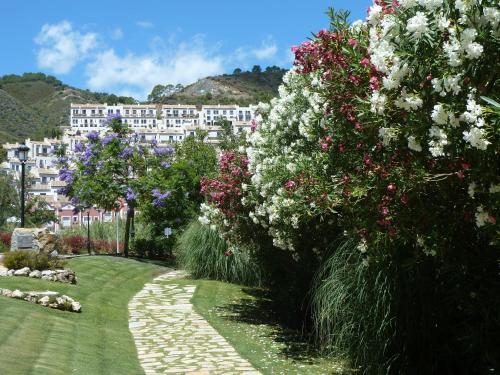 a garden with flowers and a building in the background at El Casar Apartments in Benahavís