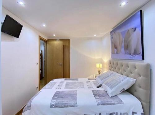 a bedroom with a large white bed and a tv at Au cœur de Cauterets, joli duplex de 55m² in Cauterets