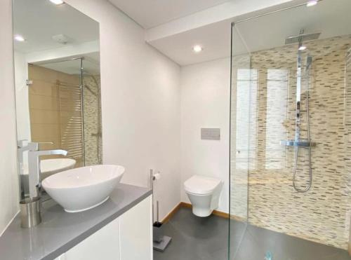 a bathroom with a sink and a toilet and a glass shower at Au cœur de Cauterets, joli duplex de 55m² in Cauterets