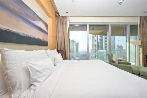 a bedroom with a white bed and a large window at FAHH Lovely Studio at Emaar Fashion Avenue in Dubai