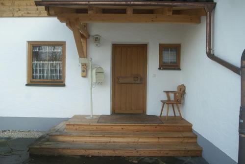 dom z drewnianymi drzwiami i krzesłem na ganku w obiekcie Ferienhaus Füchslein w mieście Bayerisch Gmain