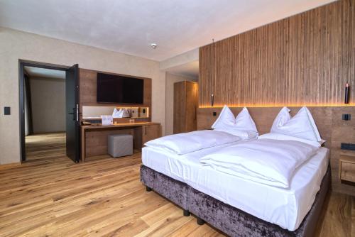 a bedroom with a large white bed and a desk at Bonfanti Design Hotel in Chienes