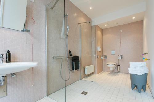 a bathroom with a shower and a sink and a toilet at Art Hotel City Leipzig in Leipzig