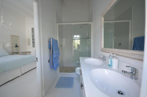 a white bathroom with two sinks and a shower at Willow Cottage in Cape Town