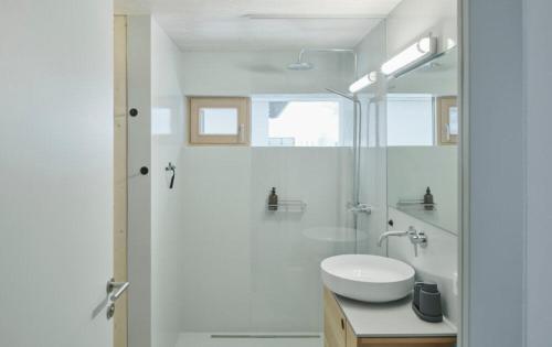 a white bathroom with a sink and a shower at Urban Alpine Penthouse with Lake View in Maurach