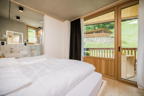 a bedroom with a large white bed and a balcony at Koasa-Hof Ganzes Ferienhaus und Sauna 5 Zimmer 240mq in Cadipietra
