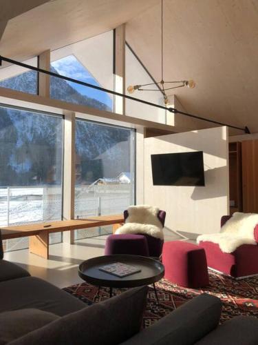 a living room with a couch and chairs and a large window at Urban Alpine Penthouse with Lake View in Maurach