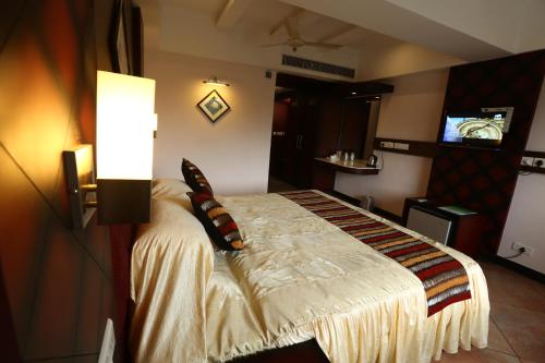 a bedroom with a bed and a television in it at PEARL ROYAL INTERNATIONAL HOTELS & RESORTS PVT LTD in Thodupuzha