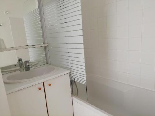 y baño blanco con lavabo y ducha. en Résidence Goélia Domaine des Oyats, en Longeville-sur-Mer