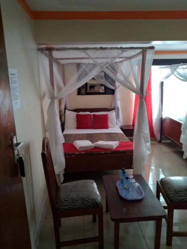 a bed with a canopy with two chairs and a table at Ocean View Nyali Boutique Hotel in Nyali