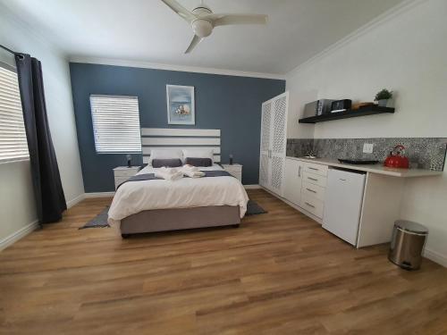 a bedroom with blue walls and a bed and a kitchen at Plett57 - Self Catering - Room No1 in Plettenberg Bay