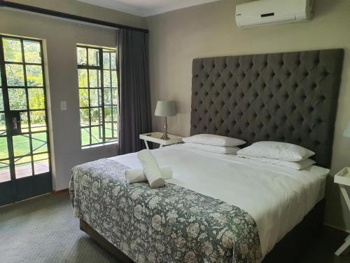 a bedroom with a large bed with a large headboard at Avoca Vale Country Hotel in Louis Trichardt